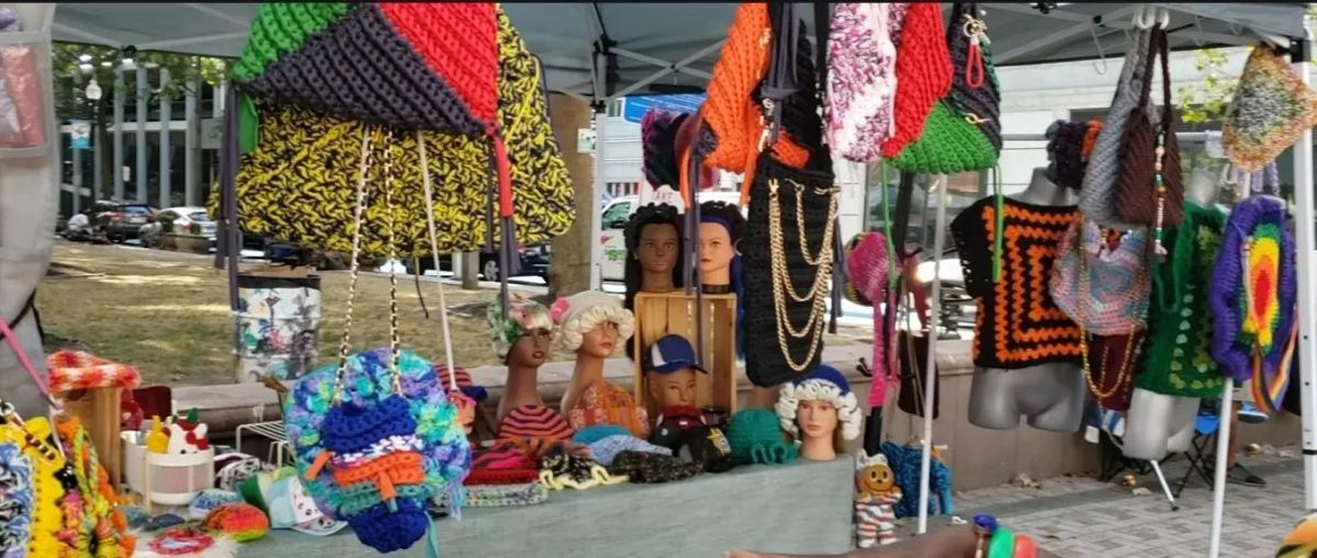 Crocheted bags and hats at an outdoor vendor tent