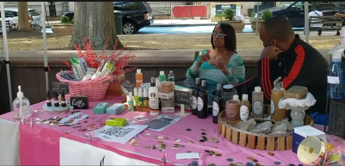 A vendor couple at a pink table of body care products